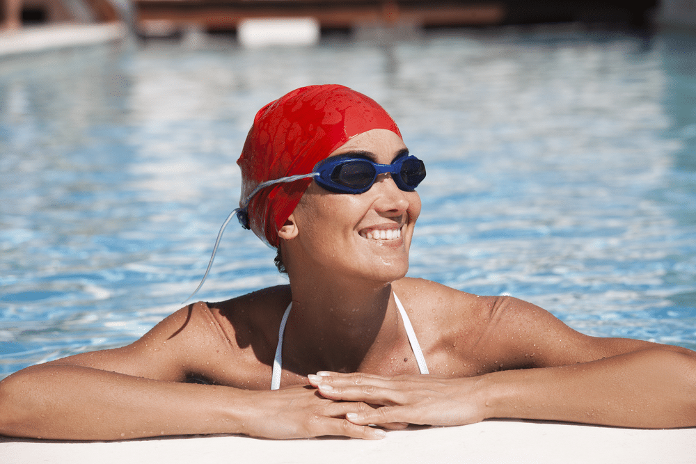 happy woman in a pool with bathing cap and swimming goggles