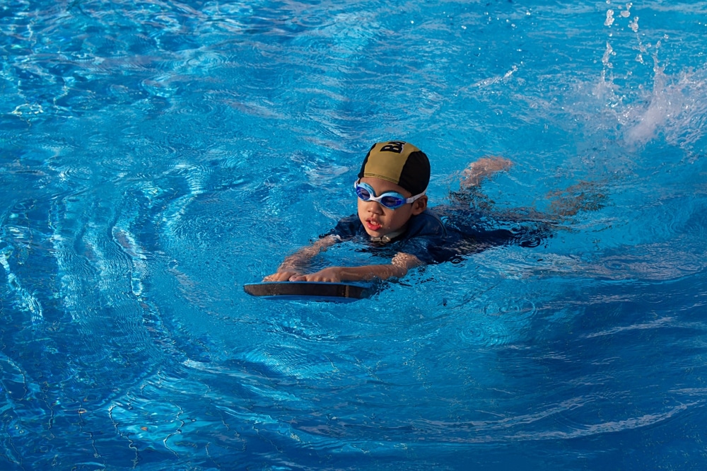 swimmer wearing goggle with dark blue suit and yellow striped black cap