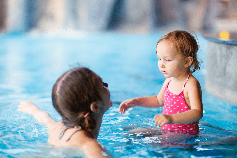 Mother and daughter playing in water in swimming pool