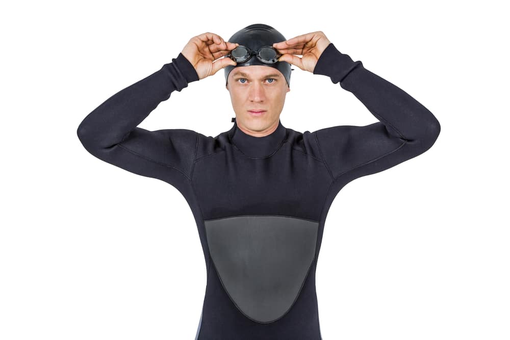 Portrait of swimmer in wetsuit wearing swimming goggles on white background 