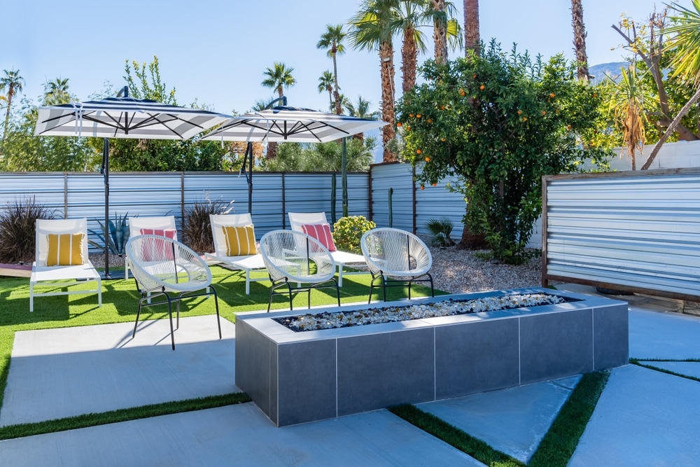 Backyard Outdoor Lounge Chairs With Umbrellas Colorful Pillows And A fireplace in palm springs 