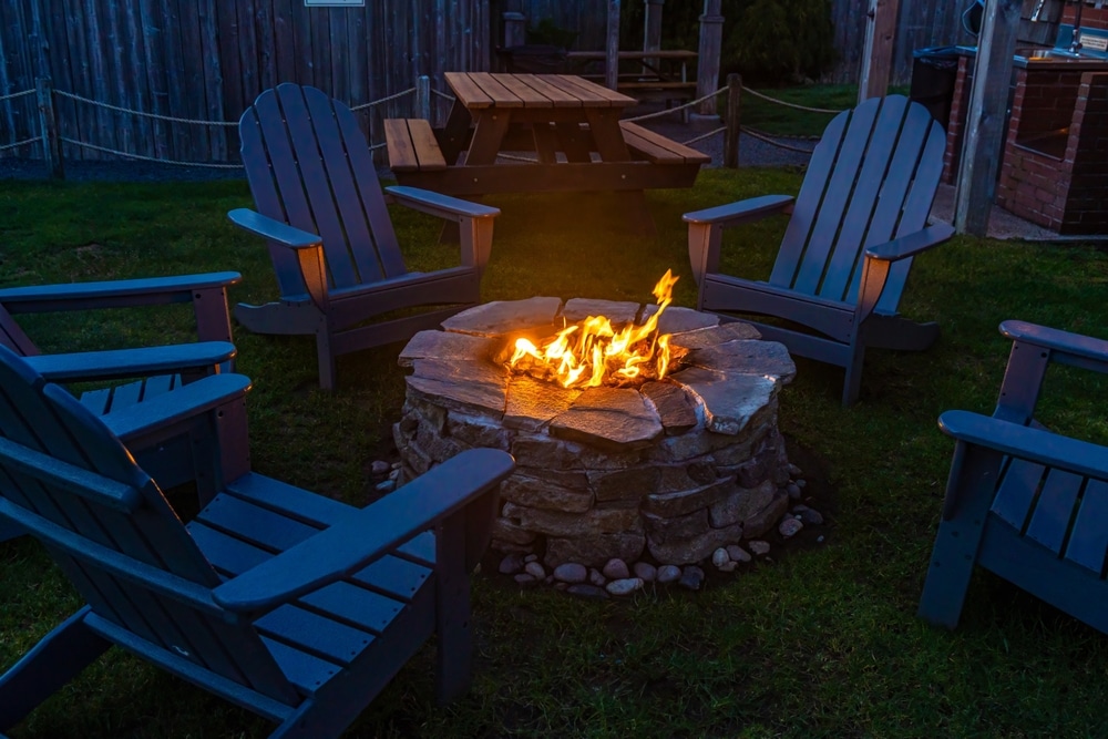 Campfire Pit Blazing Fire Surrounded By Adirondack Chairs At Night