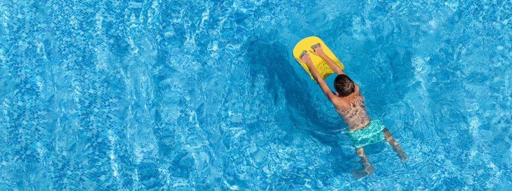 Boy Child Swim In Swimming Pool Using Board 