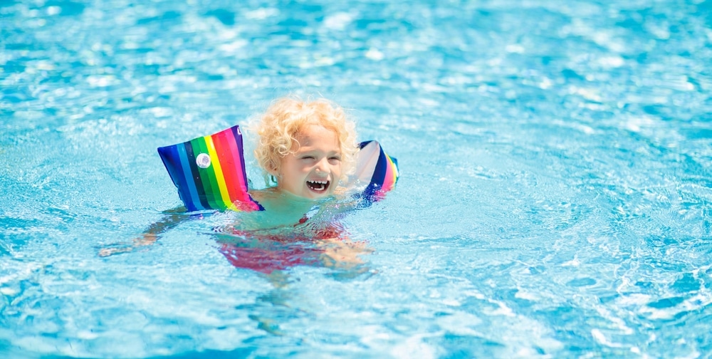 Child In Swimming Pool Wearing Colorful Inflatable Armbands 