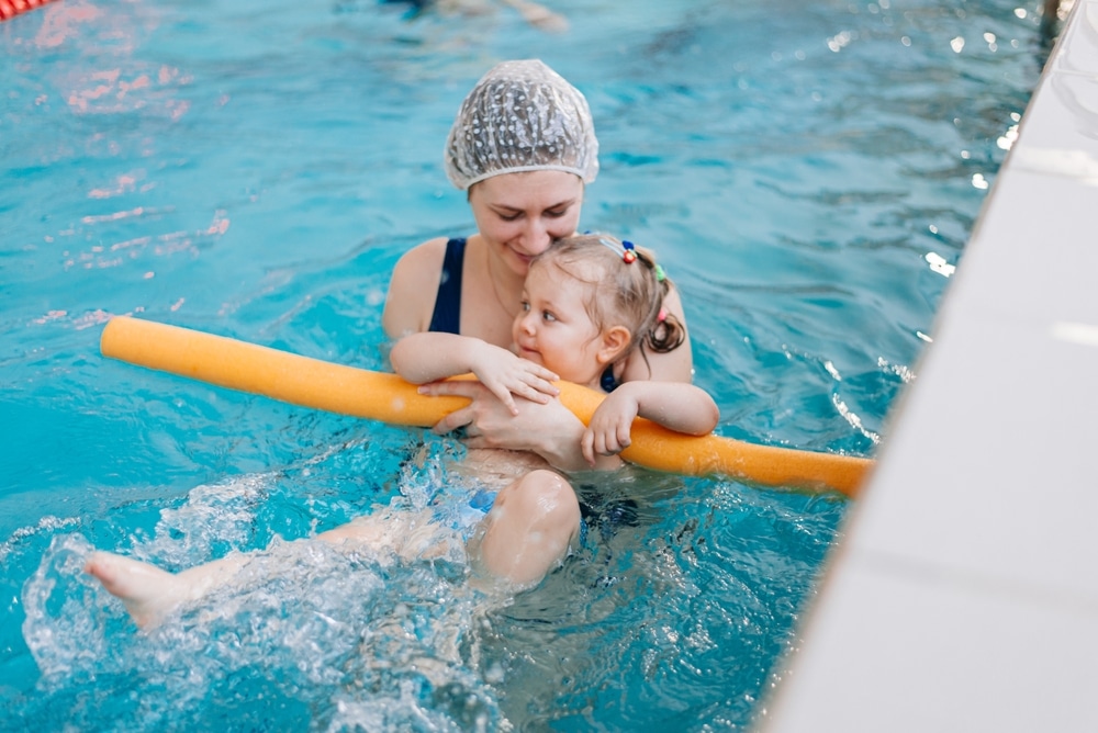 Happy Little Girl Learning To Swim With Pool Noodle